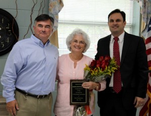 Cam DeArman, left, and Mark DeArman present their mother Martha Burns DeArman with a plaque and flowers to recognize her dedication to Burns Nursing & Rehab.
